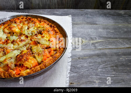 Vegetable and cheese pie in vintage pan on white linen napkin on wooden rustic background Stock Photo