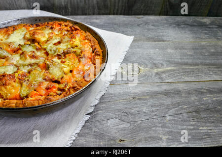Vegetable and cheese pie in vintage pan on white linen napkin on wooden rustic background Stock Photo