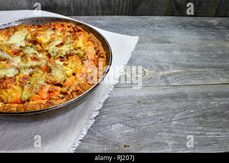 Vegetable and cheese pie in vintage pan on white linen napkin on wooden rustic background Stock Photo