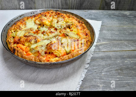 Vegetable and cheese pie in vintage pan on white linen napkin on wooden rustic background Stock Photo