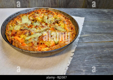 Vegetable and cheese pie in vintage pan on white linen napkin on wooden rustic background Stock Photo