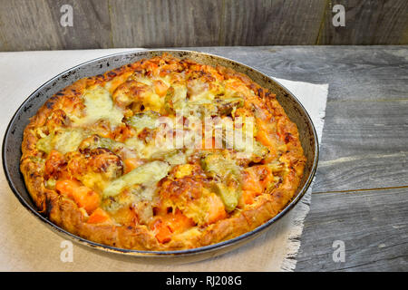 Vegetable and cheese pie in vintage pan on white linen napkin on wooden rustic background Stock Photo