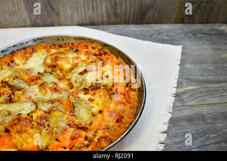 Vegetable and cheese pie in vintage pan on white linen napkin on wooden rustic background Stock Photo