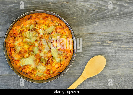 Vegetable and cheese pie in vintage pan with wooden spoon on grey wooden rustic background. Stock Photo