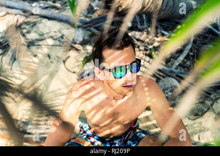 Young handsome man in sunglasses at the beach Stock Photo