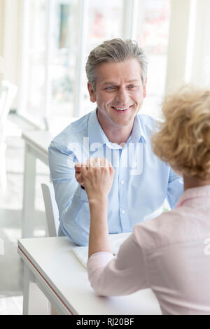 Smiling mature couple holding hands while sitting at table in restaurant Stock Photo