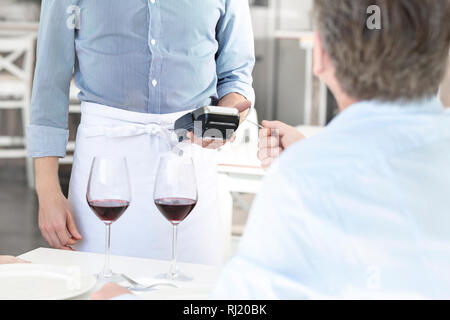 Mature customer paying through credit card at restaurant Stock Photo