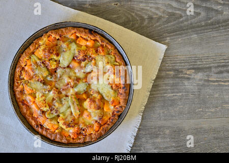 Vegetable and cheese pie in vintage pan on white linen napkin on wooden rustic background Stock Photo