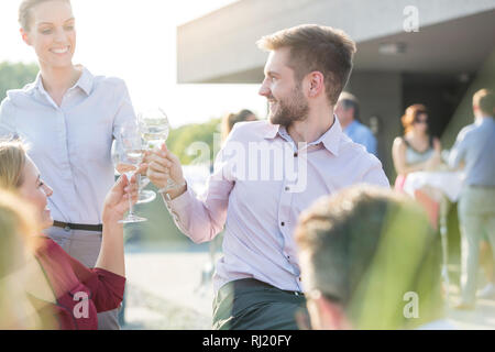 Smiling young business colleagues toasting wineglasses during success party on rooftop Stock Photo