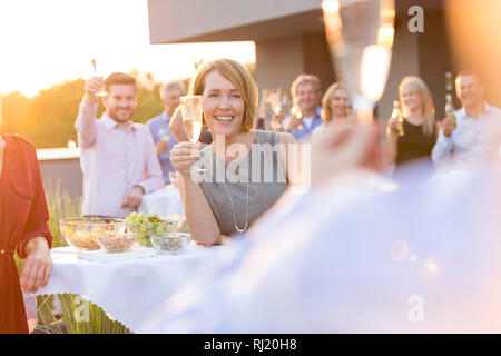 Smiling colleagues toasting wineglasses during success party on rooftop Stock Photo