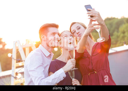 Young businesswoman taking selfie with colleagues during rooftop party Stock Photo