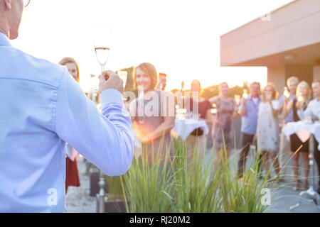 Mature businessman toasting wineglass with colleagues during success party on rooftop Stock Photo