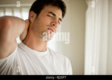 Young man rubbing his neck in pain. Stock Photo