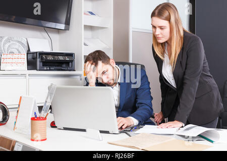Frustrated female and male sales managers working in showroom, looking at laptop monitor Stock Photo