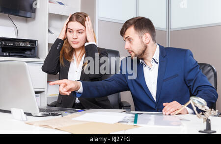 Frustrated female and male sales managers working in showroom, looking at laptop monitor Stock Photo