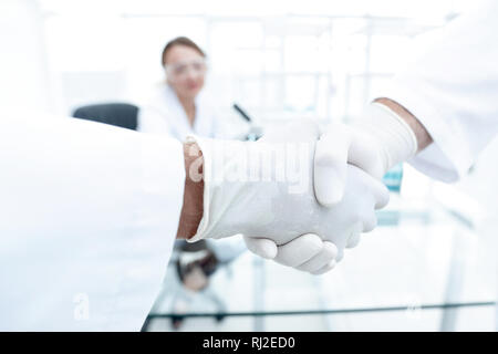 Doctors in lab coats greeting each other with handshake Stock Photo