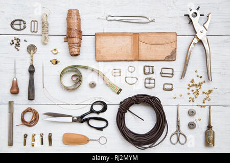 Leather craft tools and utensils on a white wooden background Stock Photo