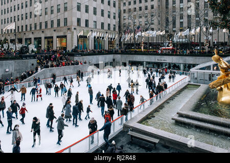 New York City - USA - DEC 17 2018: Seasonal ice skating rink with a golden statue, in a famed complex with upscale shops & restaurants in Rockefeller 