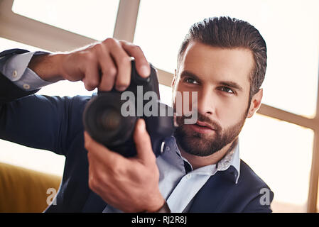Handsome young businessman in stylish suit is holding camera and going to make a photo. Business look. Close-up Stock Photo