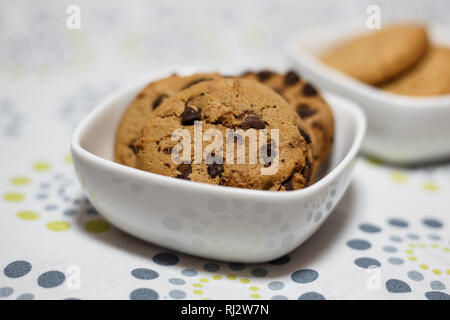 Close-up view of two different kind of cookies, oatmeal and chocolate chip cookies in the white bowls. Stock Photo