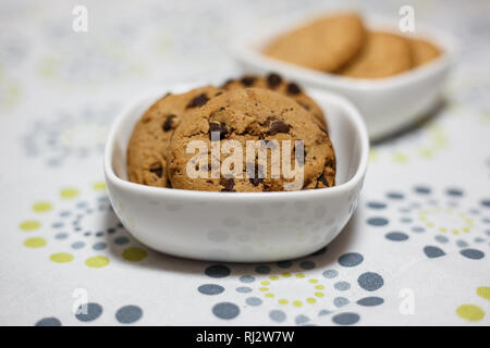 Close-up view of two different kind of cookies, oatmeal and chocolate chip cookies in the white bowls. Stock Photo