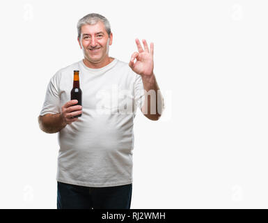 Handsome senior man drinking beer bottle over isolated background doing ok sign with fingers, excellent symbol Stock Photo