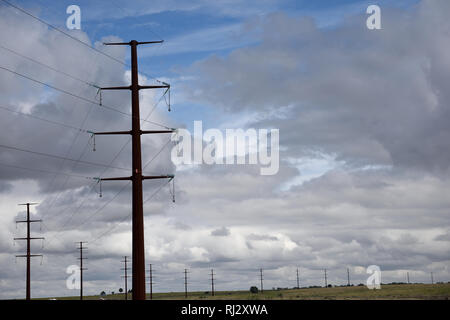 Long row of electricity transmission towers and high voltage power lines with a stormy sky in far north Texas, USA Stock Photo