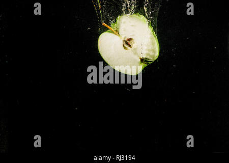 Half of apple falls in water on black background Stock Photo