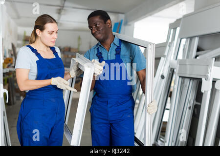 Two masters are conflicting in time working with window frame in the window workshop. Stock Photo