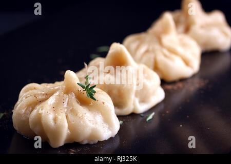 Oriental dumplings with thymine on a dark ceramic plate Stock Photo