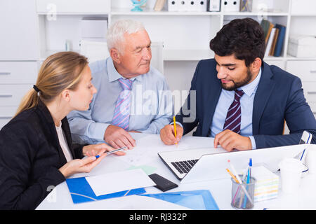 Managers are writing financial reports and discussing with mature boss in the office. Stock Photo