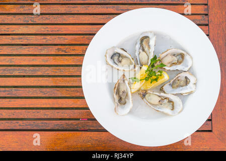 Selective focus point on fresh oysters shell with lemon - Top of view Stock Photo