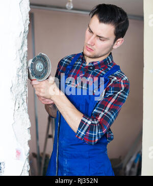 Construction worker cutting concrete wall by using handheld circular saw Stock Photo