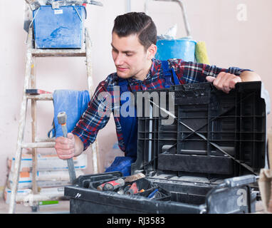 Handyman searching in his toolbox for necessary tools Stock Photo
