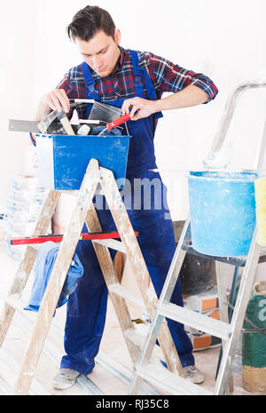 Serious worker repairing room and looking for necessary tool in toolbox Stock Photo