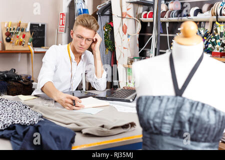 Confident  male  tailor using laptop and graphics tablet for creating pattern at sewing atelier Stock Photo