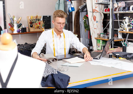 Professional male tailor at work – creating pattern using laptop and graphics tablet at his workplace Stock Photo