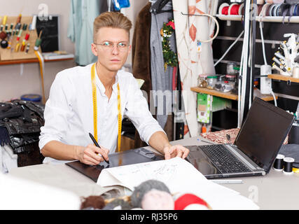 Young male tailor creating  pattern using graphics tablet at sewing atelier Stock Photo