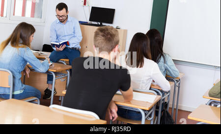 Man teacher is giving interesting lecture for students in the classroom Stock Photo