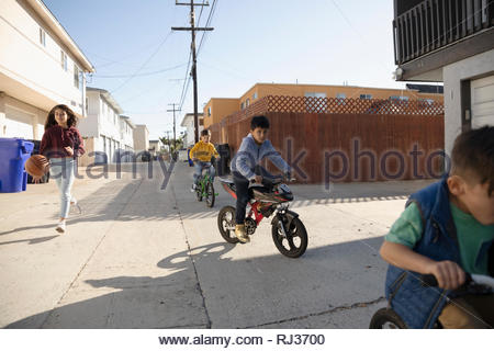 Latinx children playing, riding bikes in alley