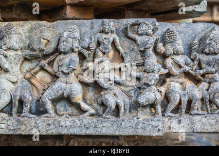 Halebidu, Karnataka, India - November 2, 2013: Hoysaleswara Temple of Shiva. Closeup of battle scene sculpture as a ribbon along wall of sanctuary. Gr Stock Photo