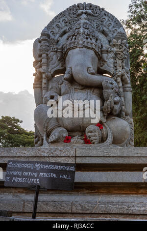 Halebidu, Karnataka, India - November 2, 2013: Hoysaleswara Temple of Shiva. Huge gray stone Ganesha statue on massive pedestal against twilight sky a Stock Photo