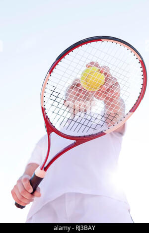 Low angle view of senior man playing tennis against clear sky on sunny day Stock Photo