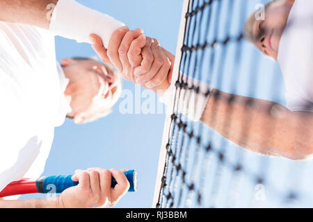 Directly below view of men greeting while standing against clear sky during match on sunny day Stock Photo