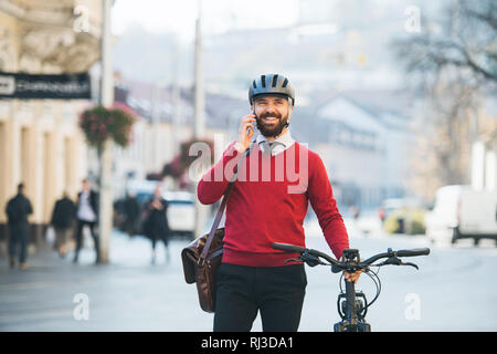 Hipster businessman commuter with bicycle and smartphone on the way to work in city. Stock Photo