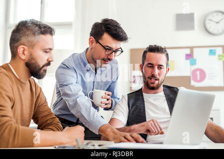 Group of young businessmen with laptop working in a modern office. Stock Photo