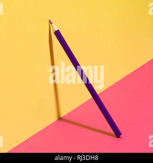 Purple school pencil on a yellow pink background. Modern conceptual art. Stock Photo