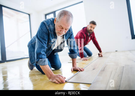 A mature man with his senior father laying vinyl flooring, a new home concept. Stock Photo