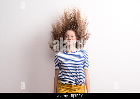 Young beautiful joyful woman with long curly hair in studio, jumping. Stock Photo