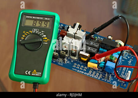 Electronic metering device multimeter showing the voltage parameter in an electronic device consisted of microchip transistor capacitor transformer Stock Photo